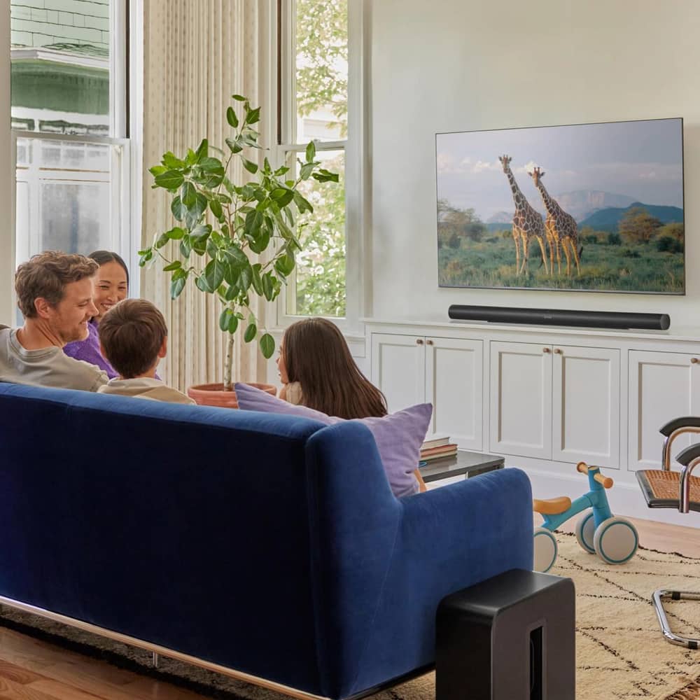 A family on the couch watching TV with a black Arc Ultra and a black Sub 4