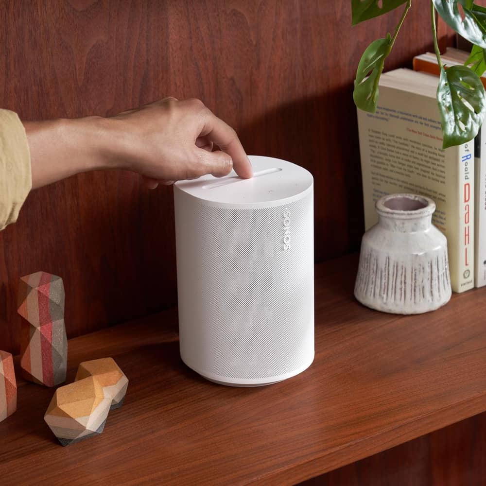 Person engaging with the top controls of a white Era 100 speaker